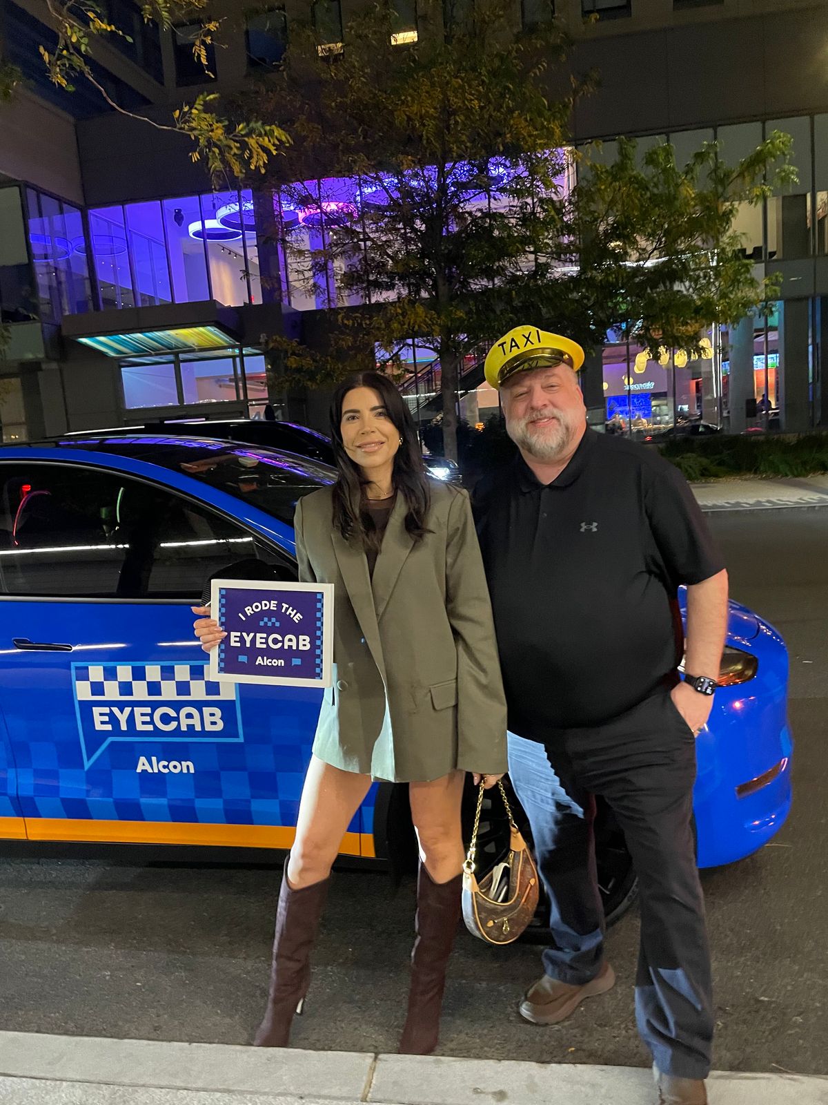 Two riders posing beside the EyeCab downtown at night