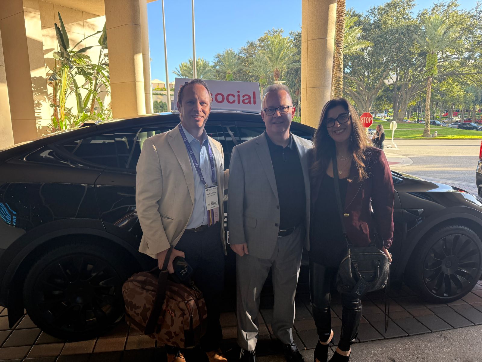 Three riders posing with the iD Social EyeCab under a hotel portico