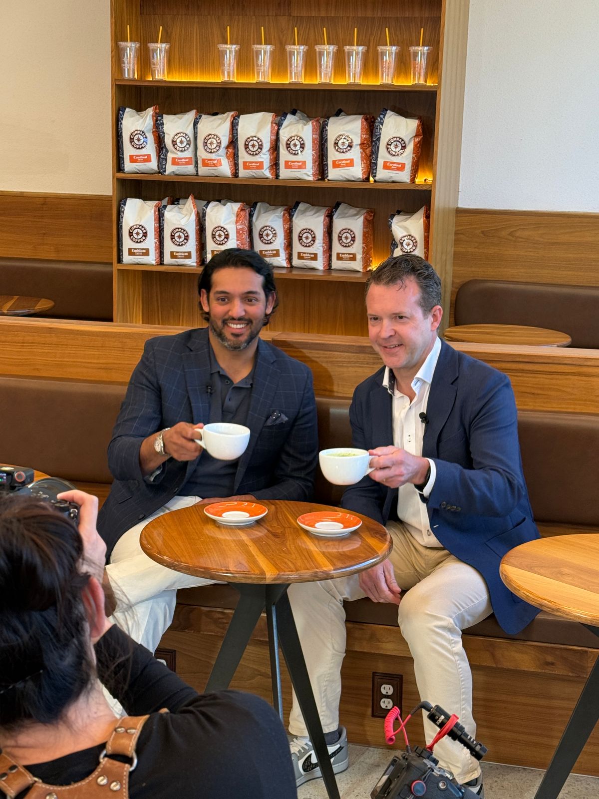 Two physicians filming a coffee-shop interview with a videographer